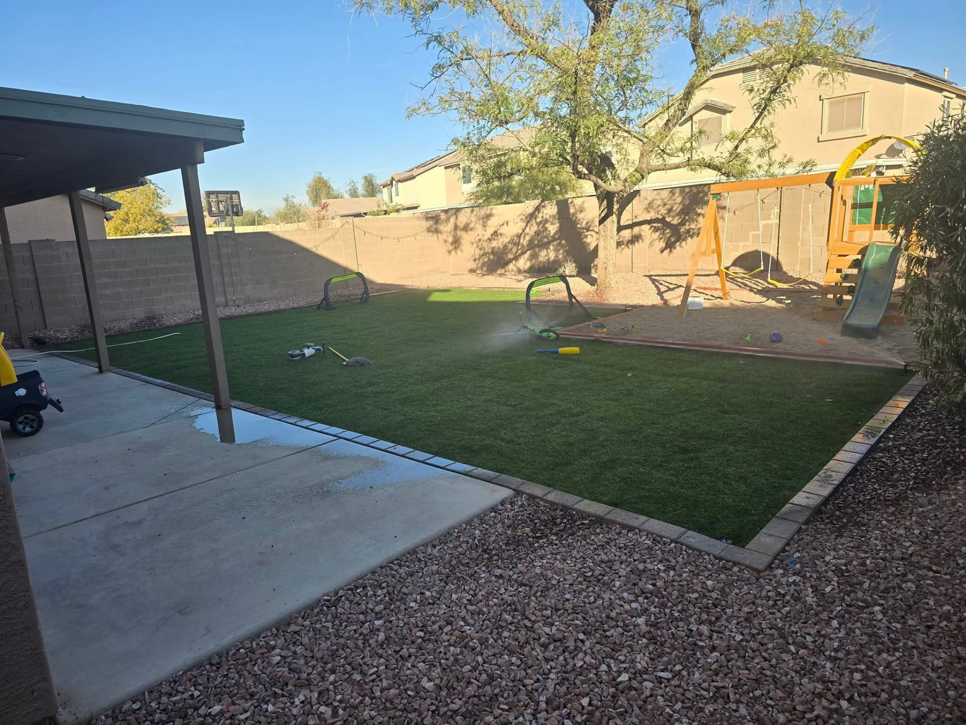 Lush artificial turf lawn with clean paver borders and a playset in the finished backyard
